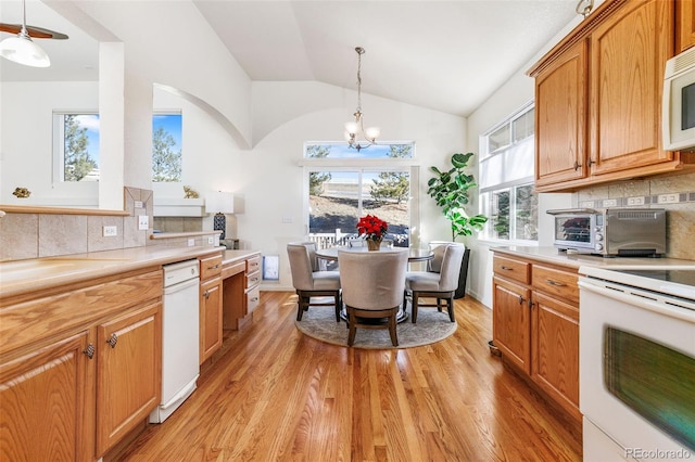 kitchen featuring tasteful backsplash, white appliances, a notable chandelier, hanging light fixtures, and lofted ceiling