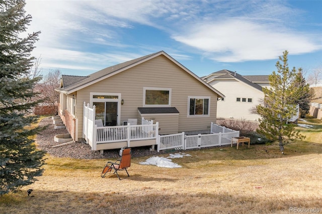 back of property with a deck and a lawn