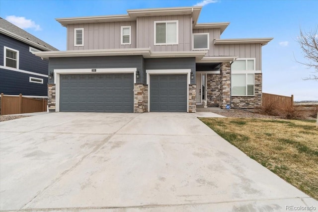 prairie-style house with board and batten siding, fence, a garage, concrete driveway, and stone siding