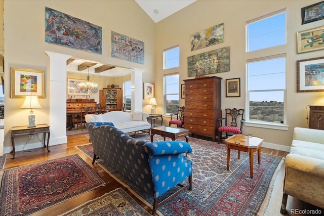 living area featuring a chandelier, wood finished floors, decorative columns, and high vaulted ceiling