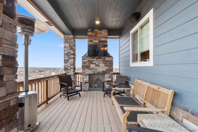 wooden terrace featuring an outdoor stone fireplace and visible vents