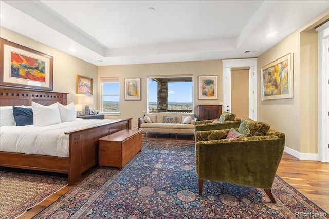 bedroom featuring a raised ceiling, baseboards, recessed lighting, and wood finished floors