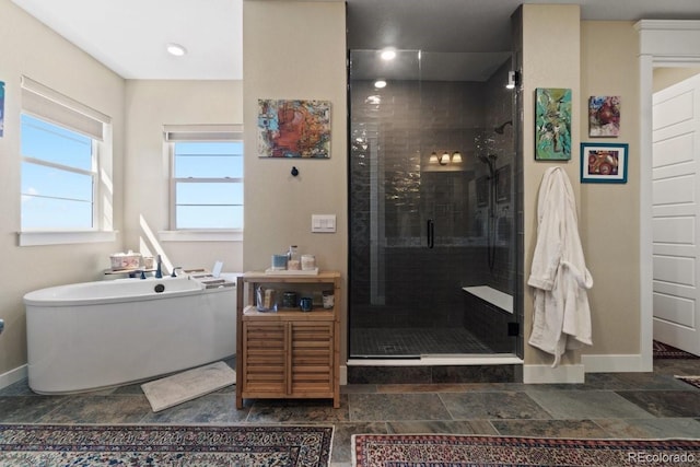bathroom featuring a freestanding bath, baseboards, a shower stall, and stone finish floor