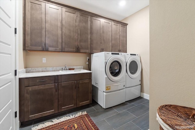 laundry room featuring cabinet space, washing machine and dryer, dark tile patterned flooring, and a sink