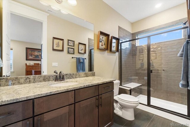 full bath with toilet, wood finished floors, visible vents, a shower stall, and vanity