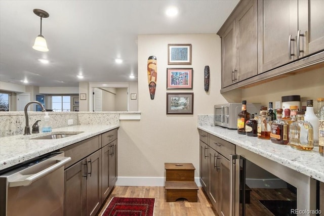 interior space featuring light wood-style flooring, beverage cooler, baseboards, a sink, and appliances with stainless steel finishes