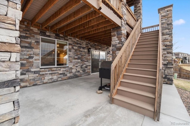 view of patio featuring fence and stairs