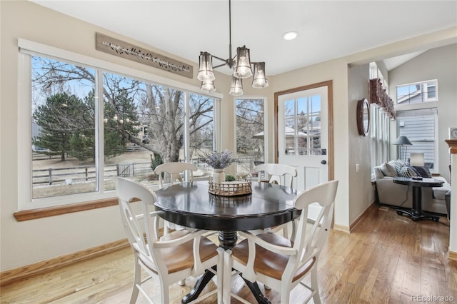 dining area with a notable chandelier, baseboards, and light wood-style floors