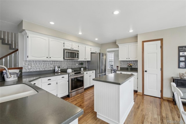 kitchen featuring dark countertops, white cabinets, light wood-style floors, and stainless steel appliances