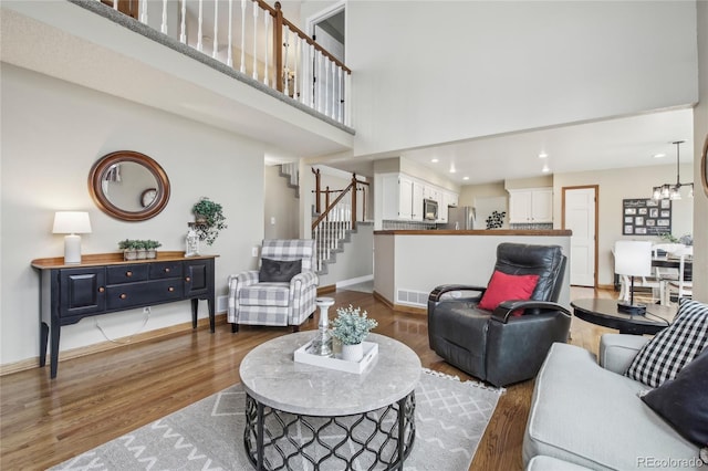 living area with visible vents, baseboards, wood finished floors, stairway, and a high ceiling