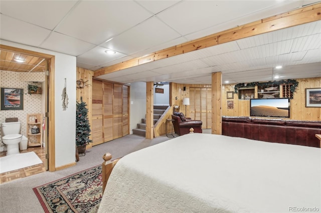 bedroom with carpet flooring, baseboards, wallpapered walls, ensuite bath, and a paneled ceiling