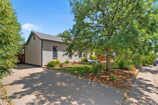 view of front facade featuring a shingled roof, fence, and concrete driveway