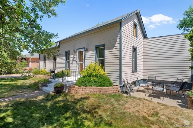 back of property with a yard and a patio