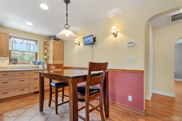 dining room featuring arched walkways, light wood-style flooring, recessed lighting, visible vents, and baseboards