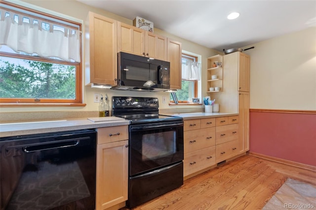 kitchen featuring light brown cabinets, black appliances, and light wood-type flooring