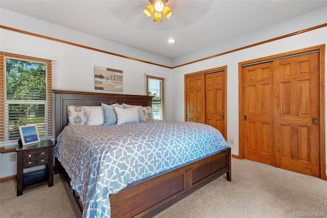 bedroom with multiple closets, light colored carpet, and ceiling fan