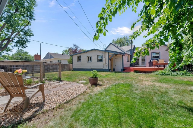 back of house featuring fence, a wooden deck, and a lawn