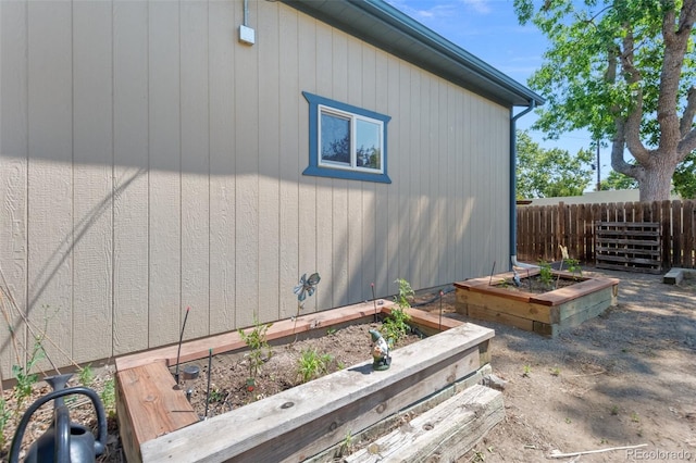 view of side of home featuring a garden and fence