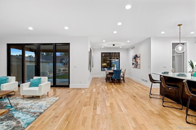 living room featuring recessed lighting, light wood-type flooring, visible vents, and baseboards