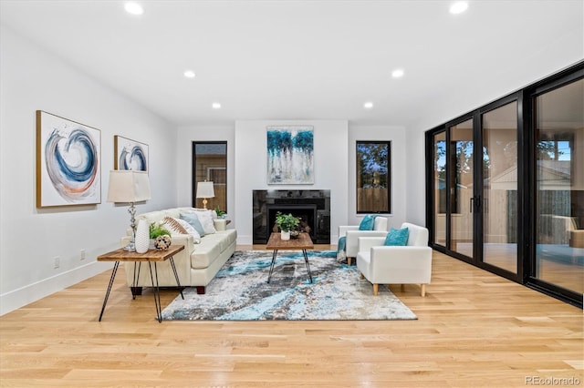 living room with recessed lighting, a premium fireplace, baseboards, and wood finished floors