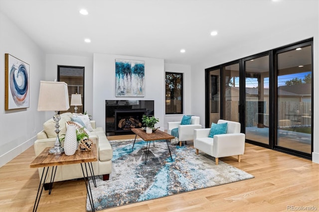 living room featuring recessed lighting, baseboards, wood finished floors, and a premium fireplace
