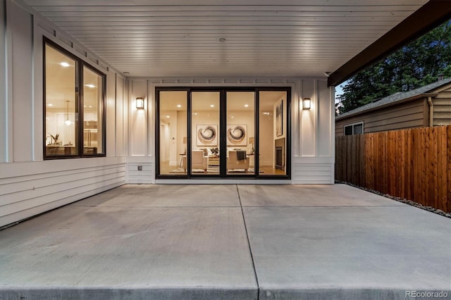 entrance to property with a patio area, board and batten siding, and fence