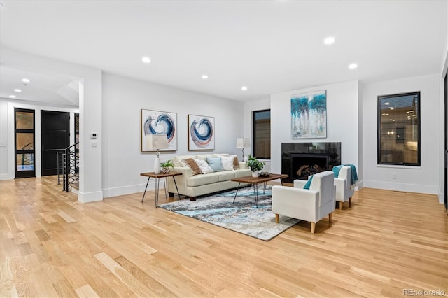 living room featuring a fireplace, light wood finished floors, baseboards, and recessed lighting