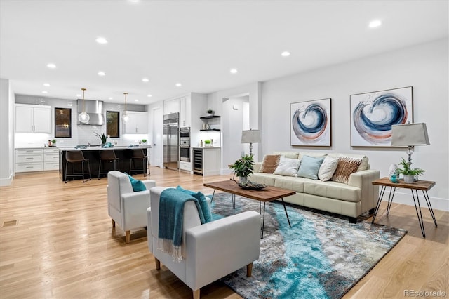 living area with recessed lighting, light wood-type flooring, and baseboards