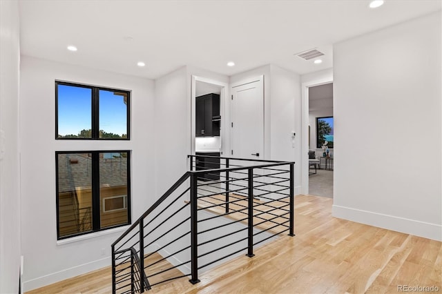 hallway with light wood-style flooring, visible vents, recessed lighting, an upstairs landing, and baseboards