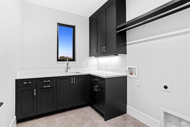 laundry area with light tile patterned floors, hookup for a washing machine, hookup for an electric dryer, a sink, and cabinet space