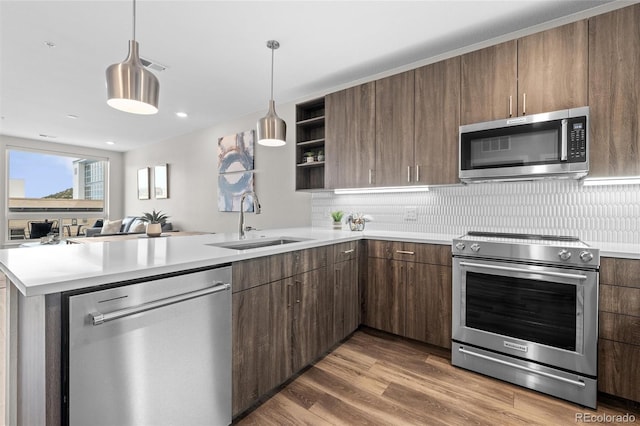 kitchen featuring a peninsula, light countertops, open shelves, stainless steel appliances, and a sink