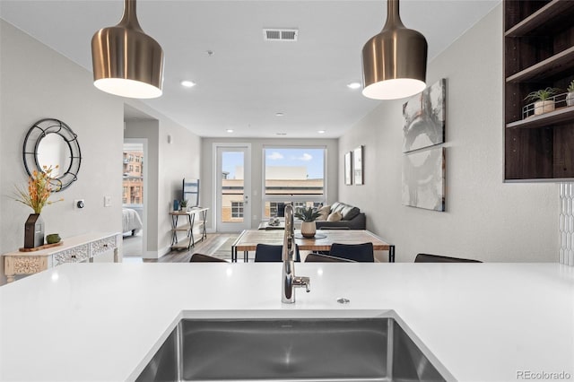 kitchen featuring light countertops, open floor plan, a sink, and visible vents