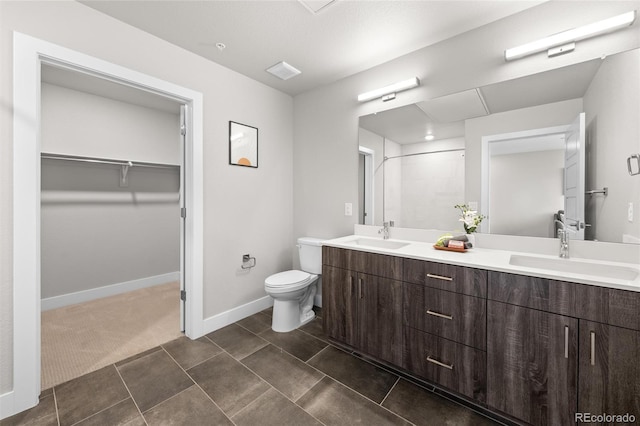 full bath with double vanity, a sink, a walk in closet, and toilet