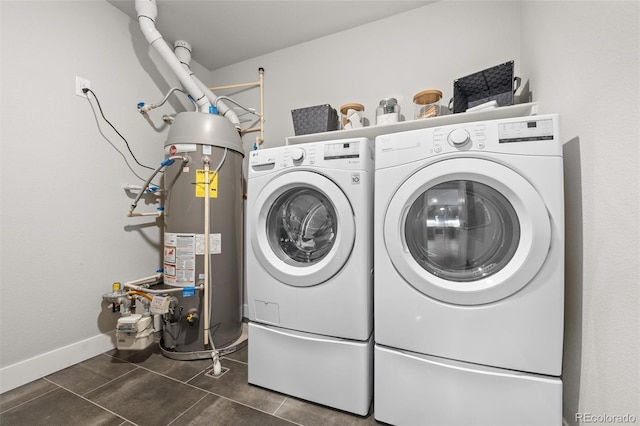 clothes washing area featuring water heater, separate washer and dryer, baseboards, tile patterned flooring, and laundry area