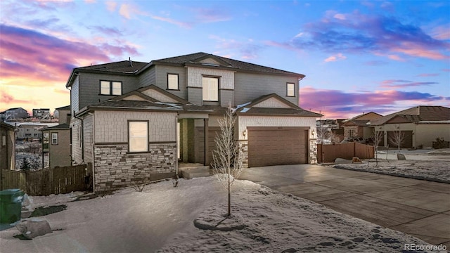 view of front of house featuring stone siding, an attached garage, concrete driveway, and fence