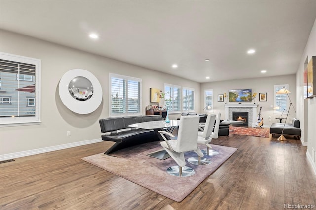 dining area with recessed lighting, a lit fireplace, and wood finished floors