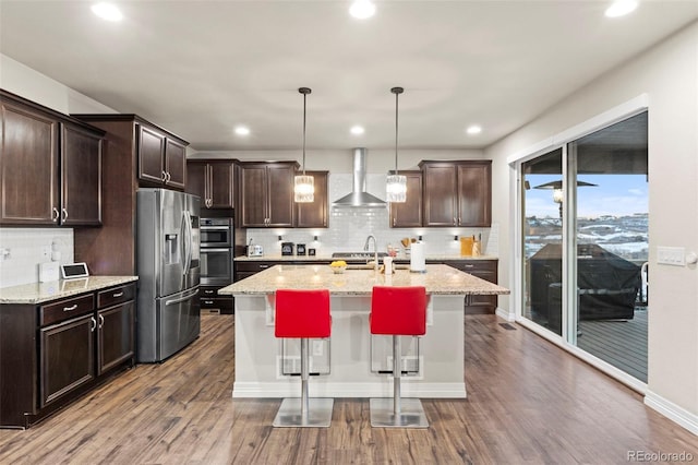 kitchen with dark brown cabinetry, appliances with stainless steel finishes, wall chimney exhaust hood, and dark wood-type flooring