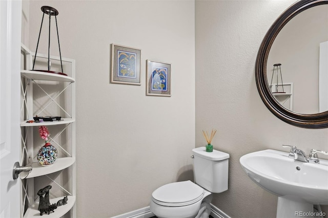 bathroom with toilet, baseboards, and a sink