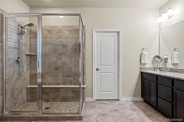 full bathroom with baseboards, vanity, and a shower stall