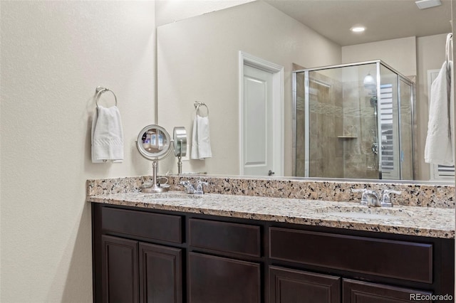 full bathroom with double vanity, a stall shower, and a sink