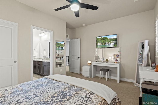 bedroom featuring visible vents, baseboards, light colored carpet, ensuite bathroom, and a ceiling fan