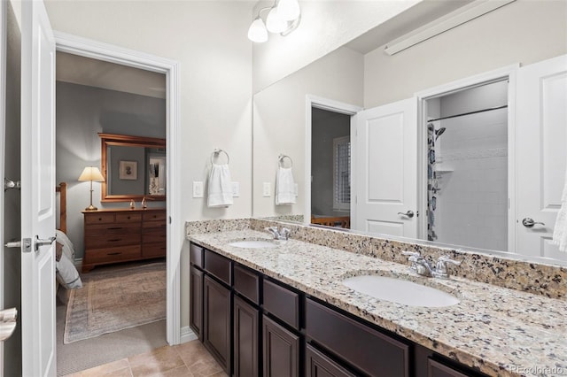 ensuite bathroom featuring a sink, a shower with shower curtain, double vanity, and tile patterned floors