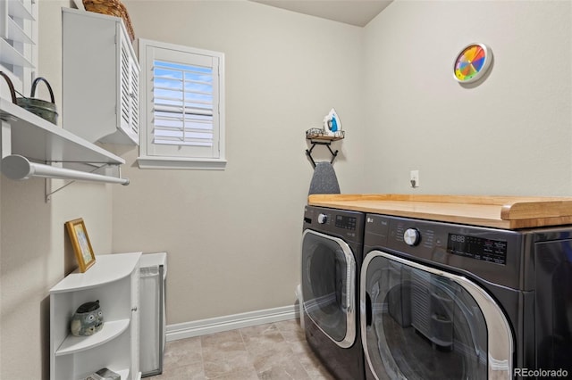 washroom featuring laundry area, baseboards, and separate washer and dryer