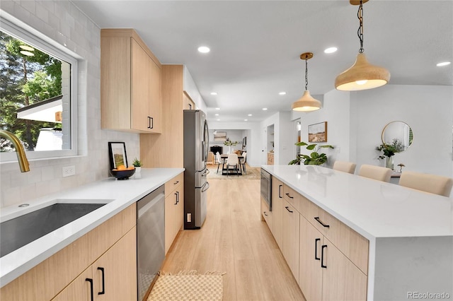 6716 W Rowland Ave, Littleton, CO 80128 - kitchen with light brown cabinetry, stainless steel appliances, a sink, light wood-type flooring, and a kitchen island