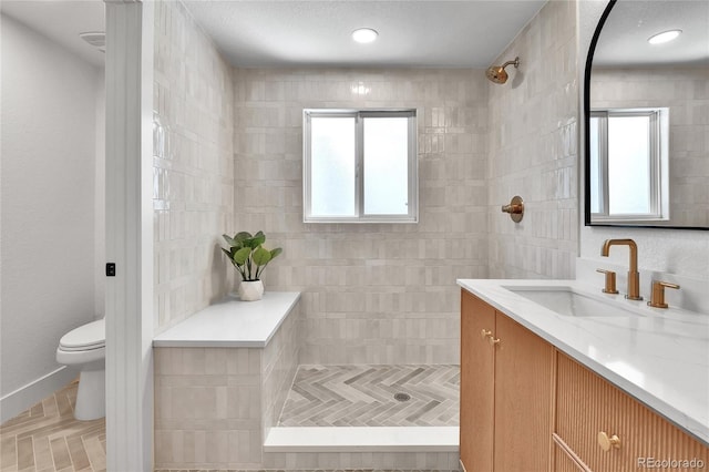 6716 W Rowland Ave, Littleton, CO 80128 - bathroom featuring vanity, tiled shower, toilet, and plenty of natural light