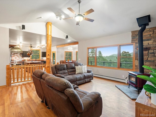 28465 Cragmont Dr, Evergreen, CO 80439 - living area featuring a baseboard radiator, ceiling fan, a wood stove, light wood-style floors, and vaulted ceiling