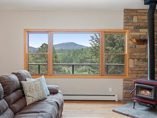 28465 Cragmont Dr, Evergreen, CO 80439 - living area featuring a wood stove, a baseboard heating unit, wood finished floors, a mountain view, and a forest view