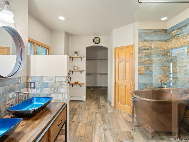 28465 Cragmont Dr, Evergreen, CO 80439 - full bath with a baseboard radiator, a freestanding tub, wood finished floors, vanity, and a spacious closet