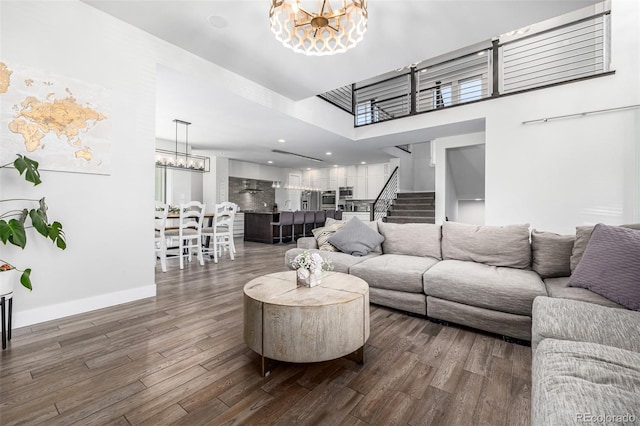 living room featuring dark wood-type flooring, a chandelier, and a towering ceiling