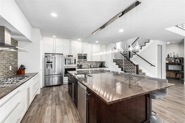 kitchen featuring stainless steel appliances, wood-type flooring, a breakfast bar area, tasteful backsplash, and sink